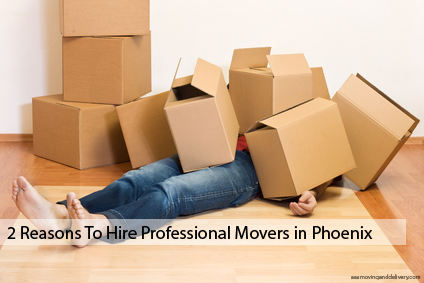 A person in blue jeans laying on the ground under a pile of moving boxes.