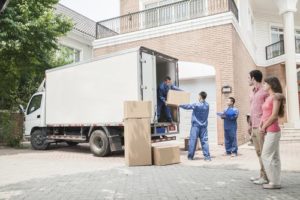 movers moving boxes into a truck with homeowners watching